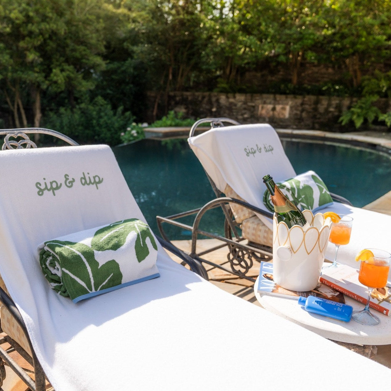 Two lounge chairs by a pool with drinks and snacks on a table, featuring 'sip & dip' text.