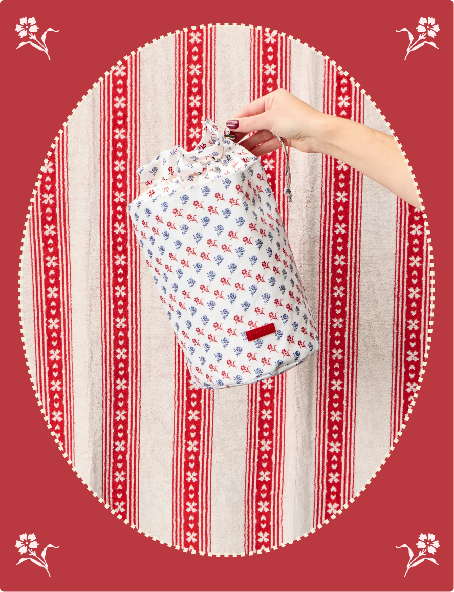 Hand holding a floral-patterned bag against a red and white striped background