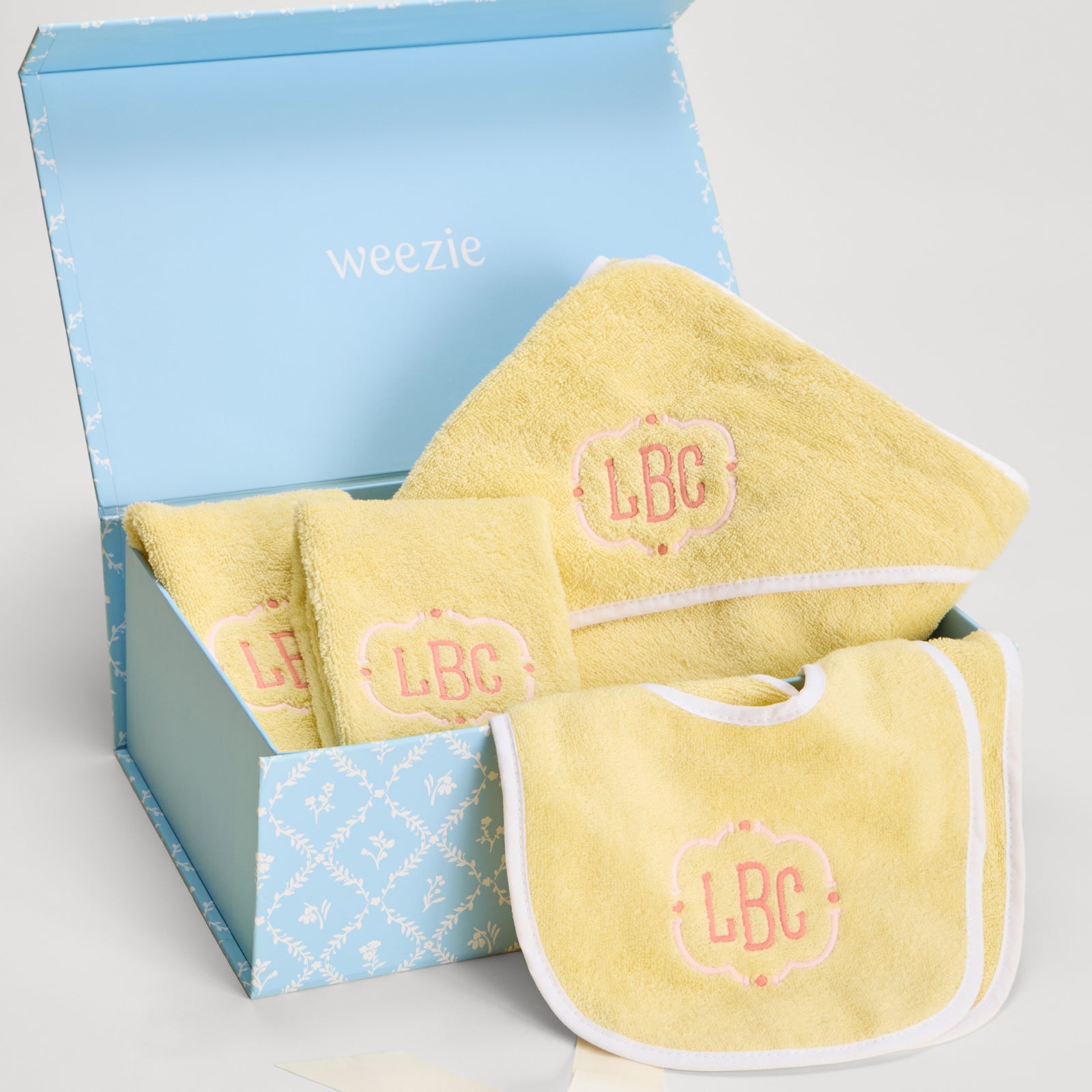 Blue Weezie gift box filled with buttercup yellow baby towel, bibs, and burp cloths.