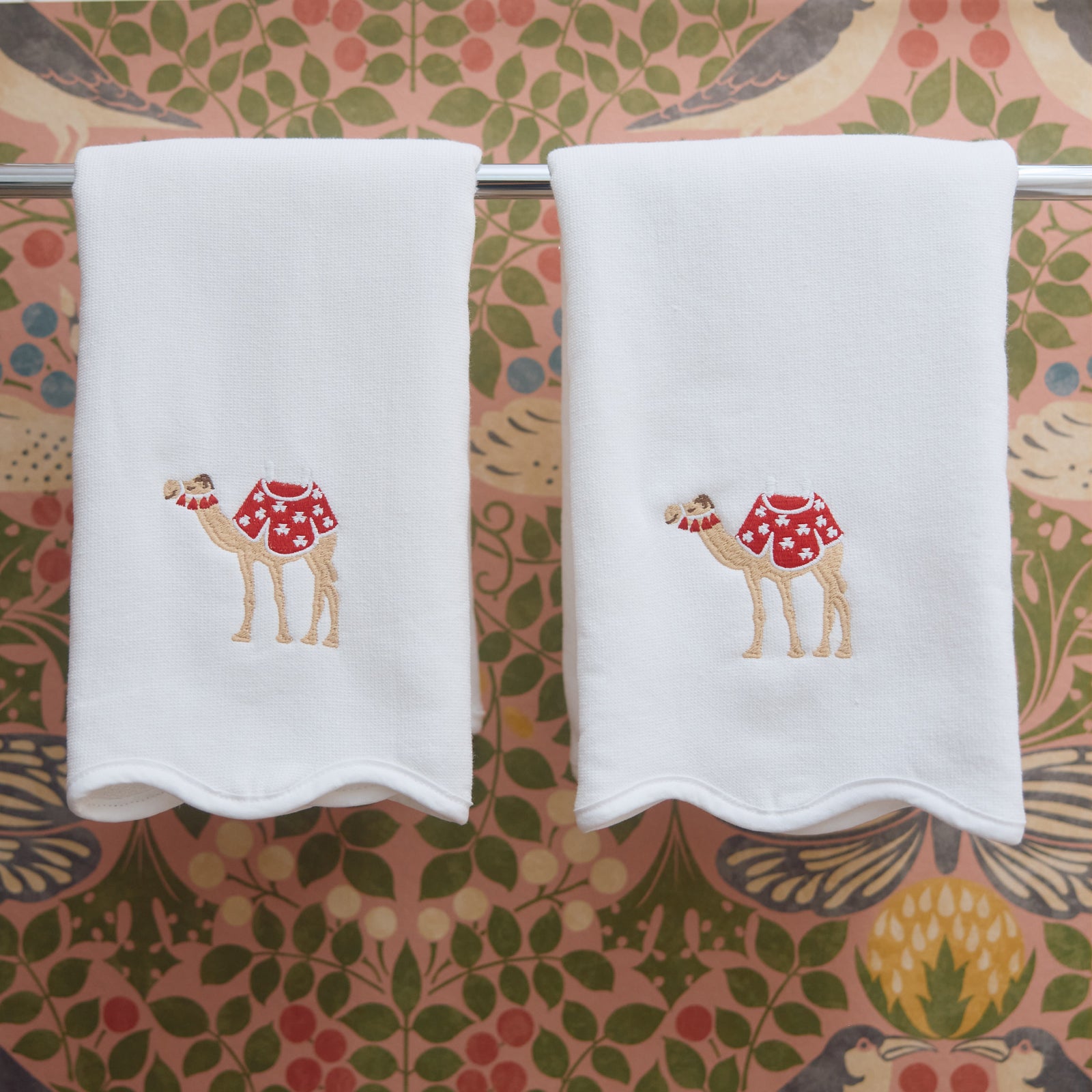 Holiday Camel scalloped powder bath towels hanging side by side against red and green floral wallpaper