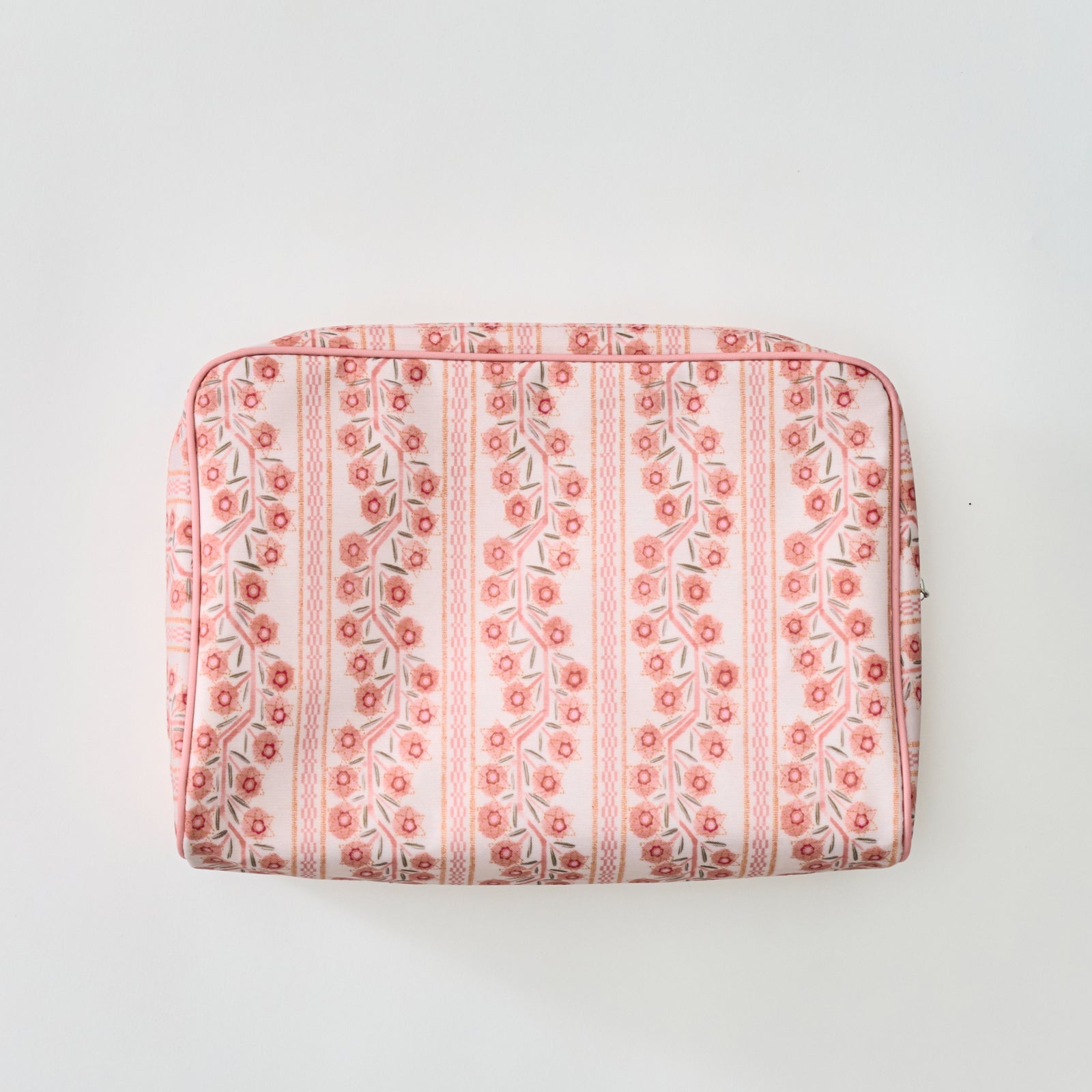 A rectangular toiletry bag featuring a pink and coral floral climbing vine stripe pattern with light pink piping, shown flat against a plain light background.