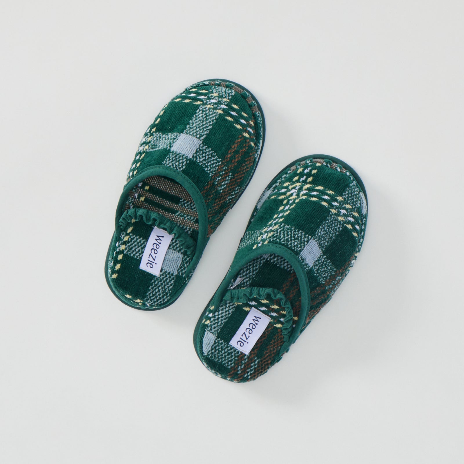 A pair of kids' green plaid terry slippers with elastic straps, shown from above.