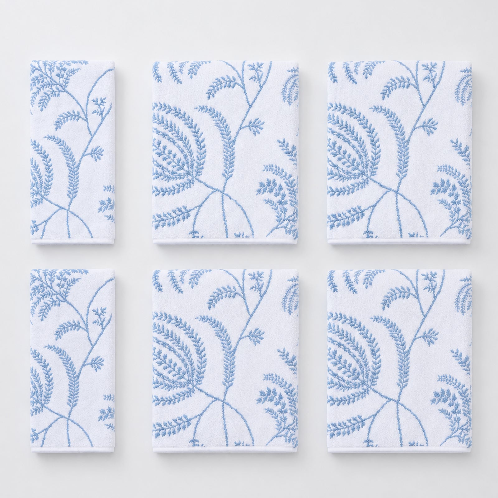 Folded white towels featuring a sky blue Lee Jofa Palmero floral pattern.