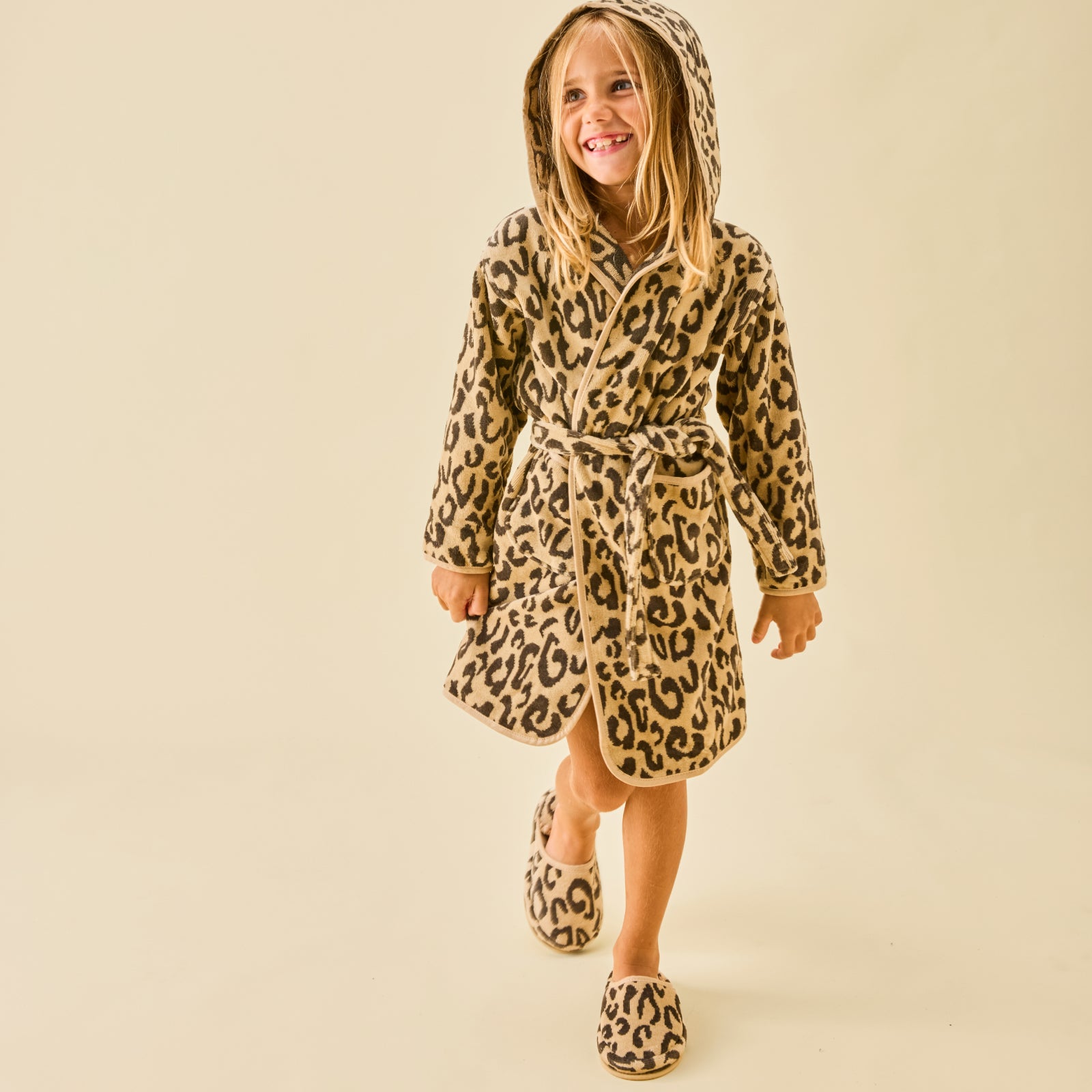 A girl wearing matching leopard fluffy slippers and robe.