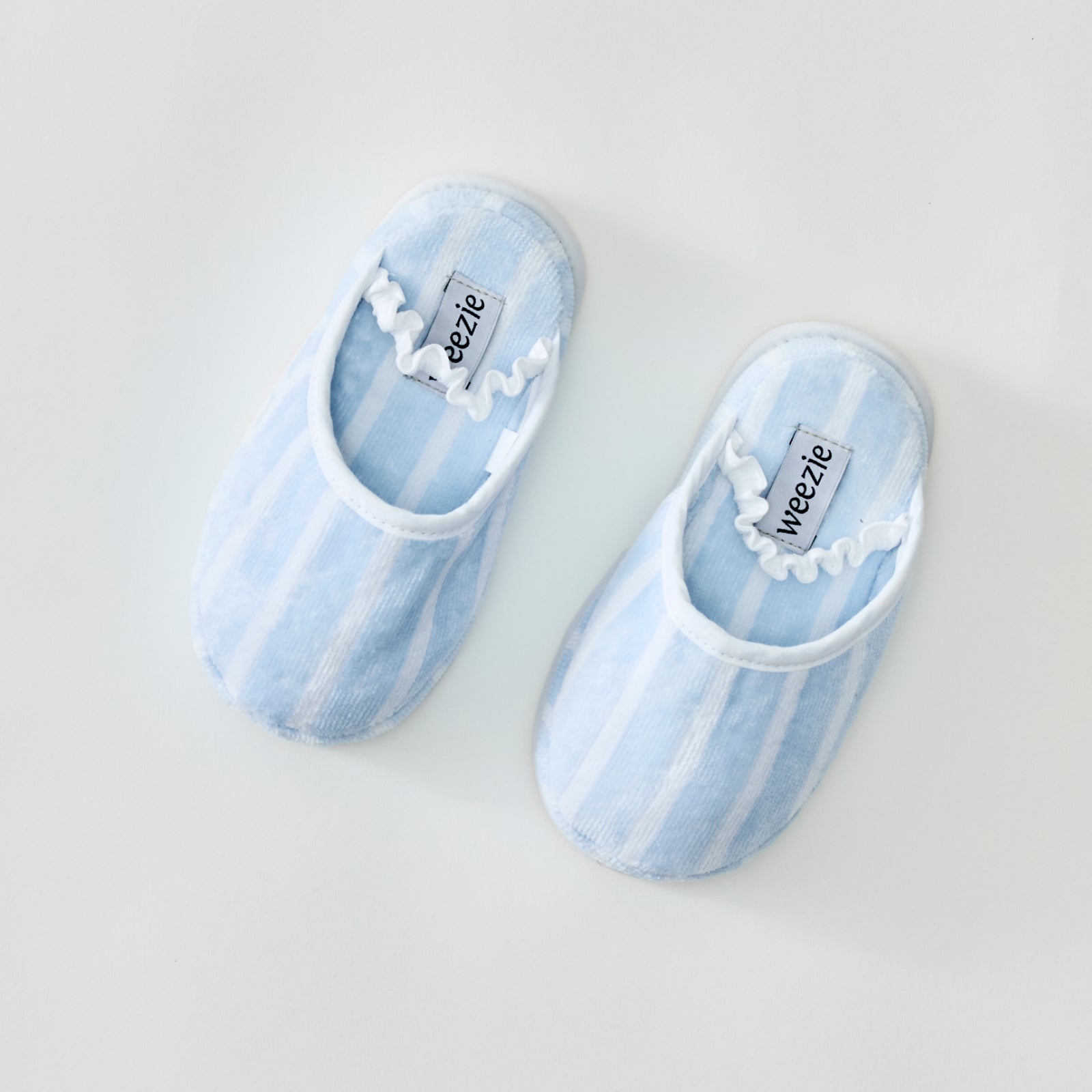 Fluffy light blue striped slippers with a white ruffled elastic strap.
