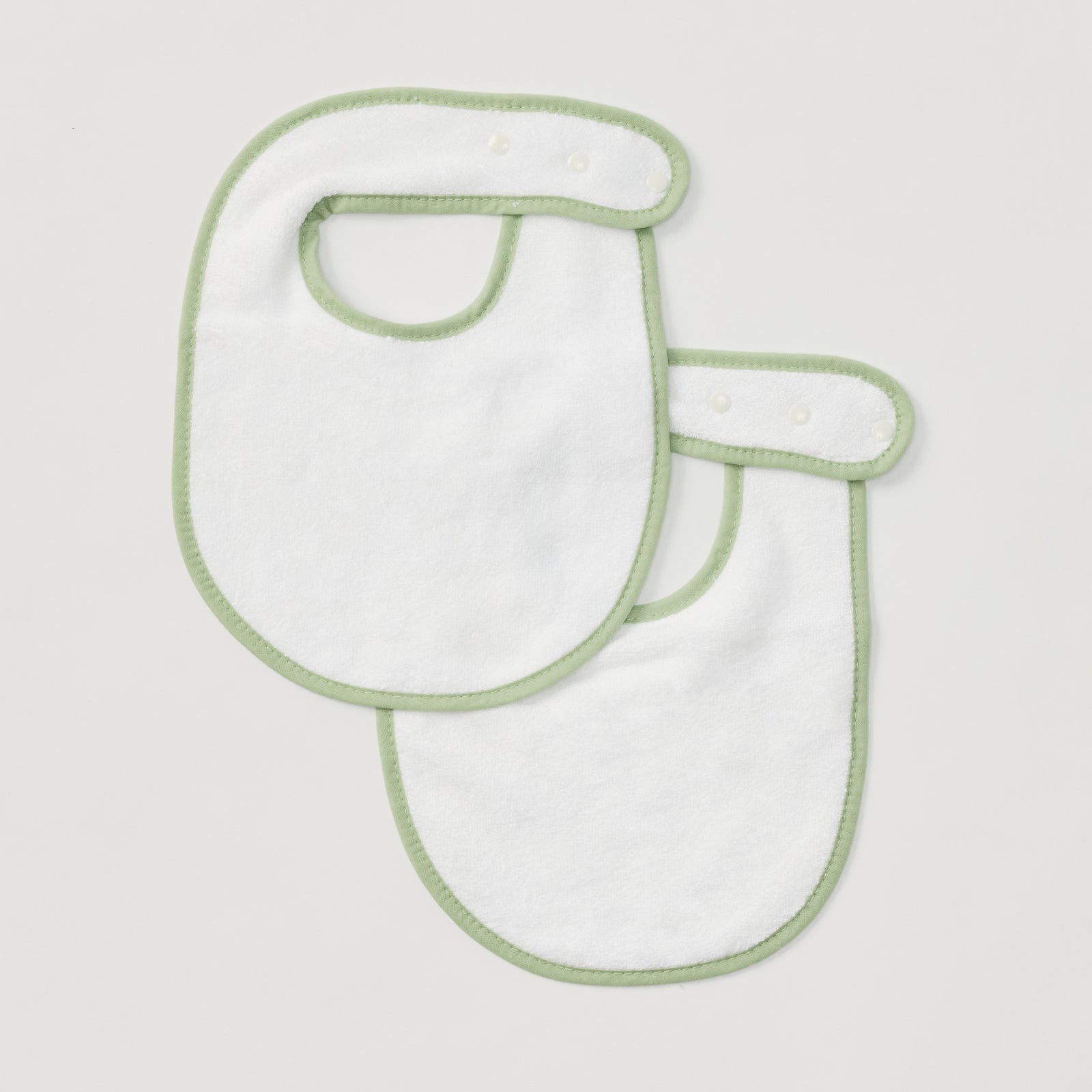 Pair of plain white baby bibs with matcha green piping and snap closures.