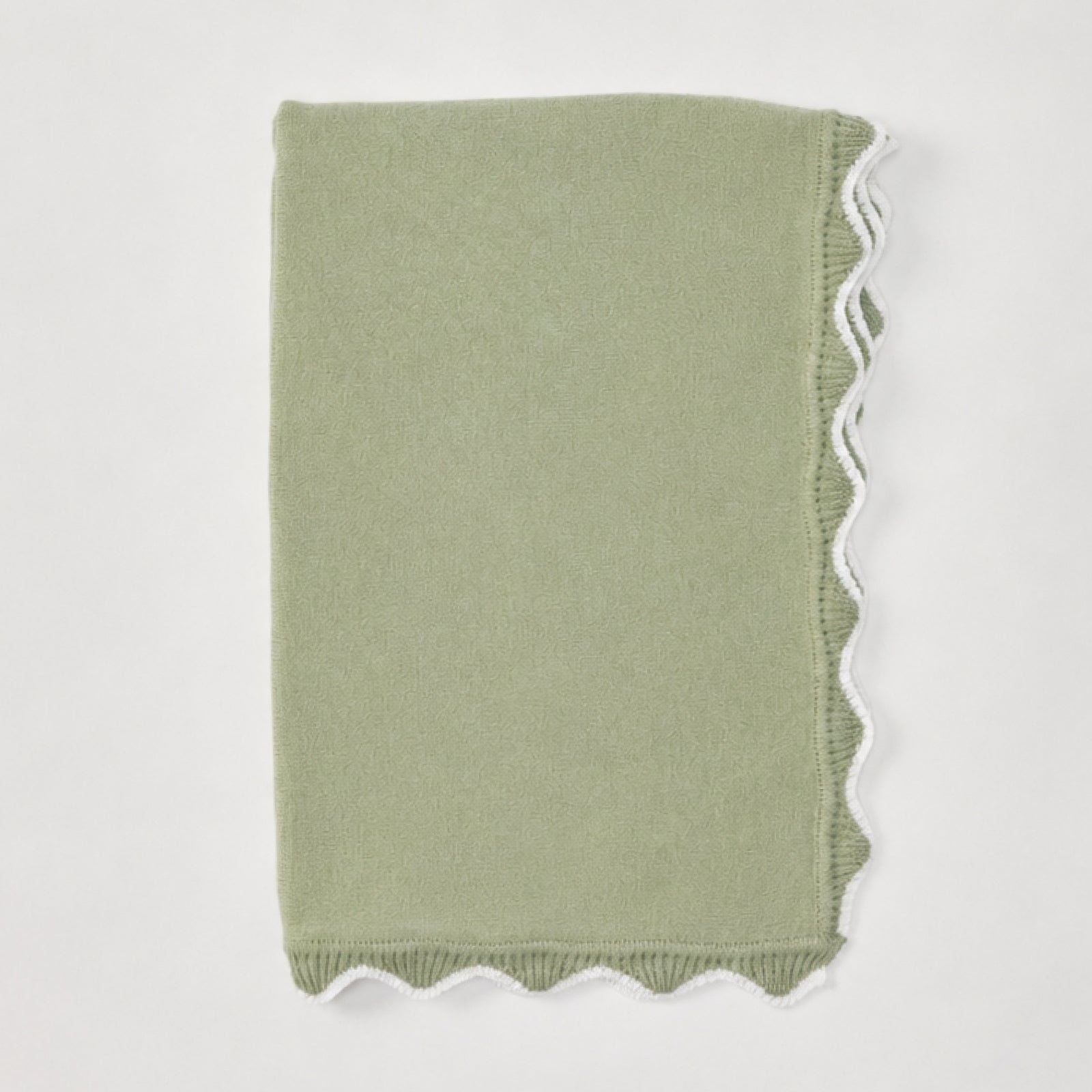 Folded matcha green baby blanket with white scalloped edges.