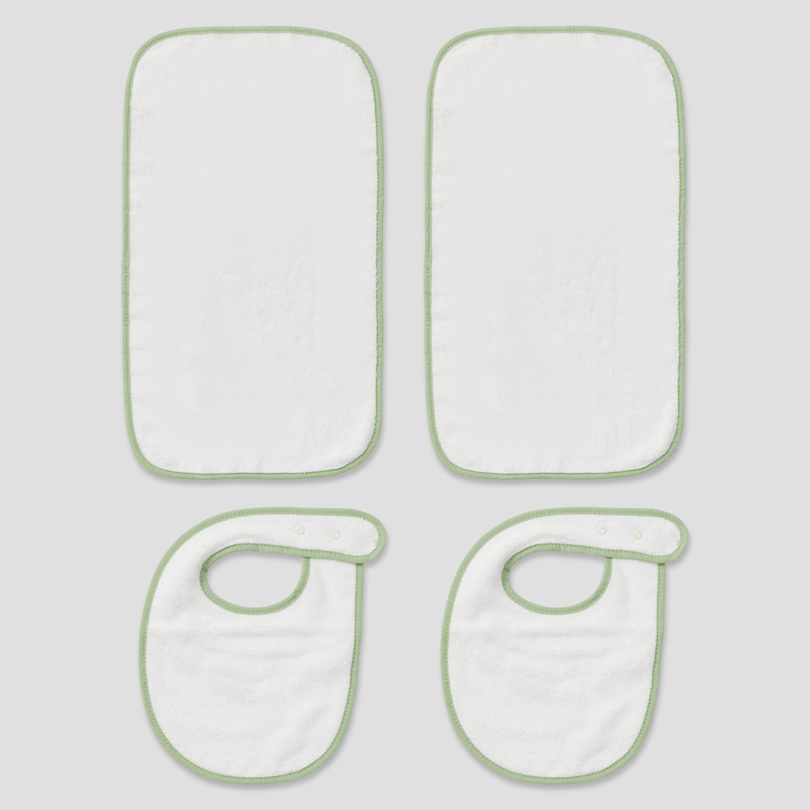 Flat lay of two white baby bibs and two burp cloths featuring matcha green trim.