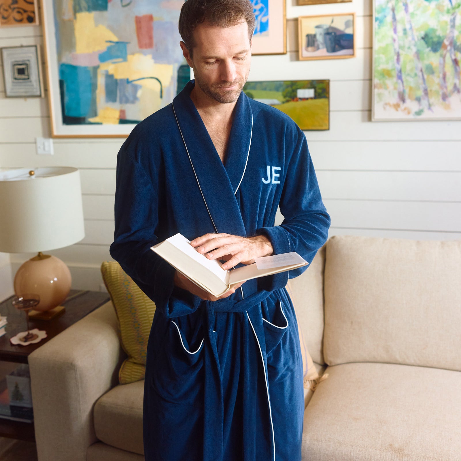 Man reading on a sofa in the Midnight lightweight robe with a monogram