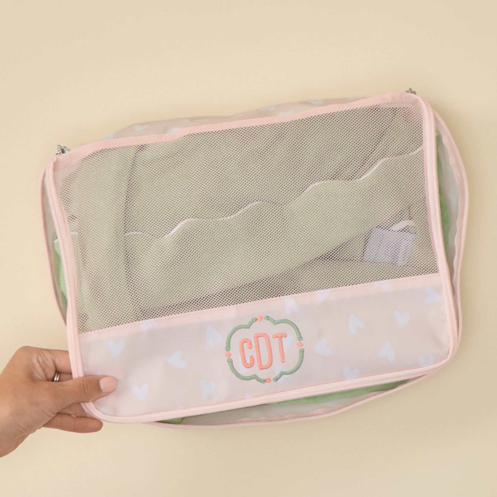 Personalized Tossed Pink Hearts packing cube featuring an embroidered 'CDT' monogram, set against a light background.