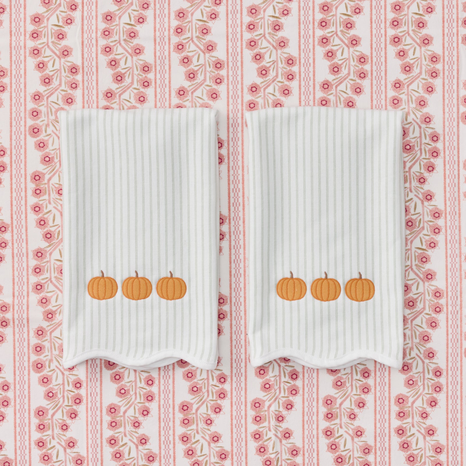 Pair of scalloped green striped kitchen towels featuring pumpkins embroidery.