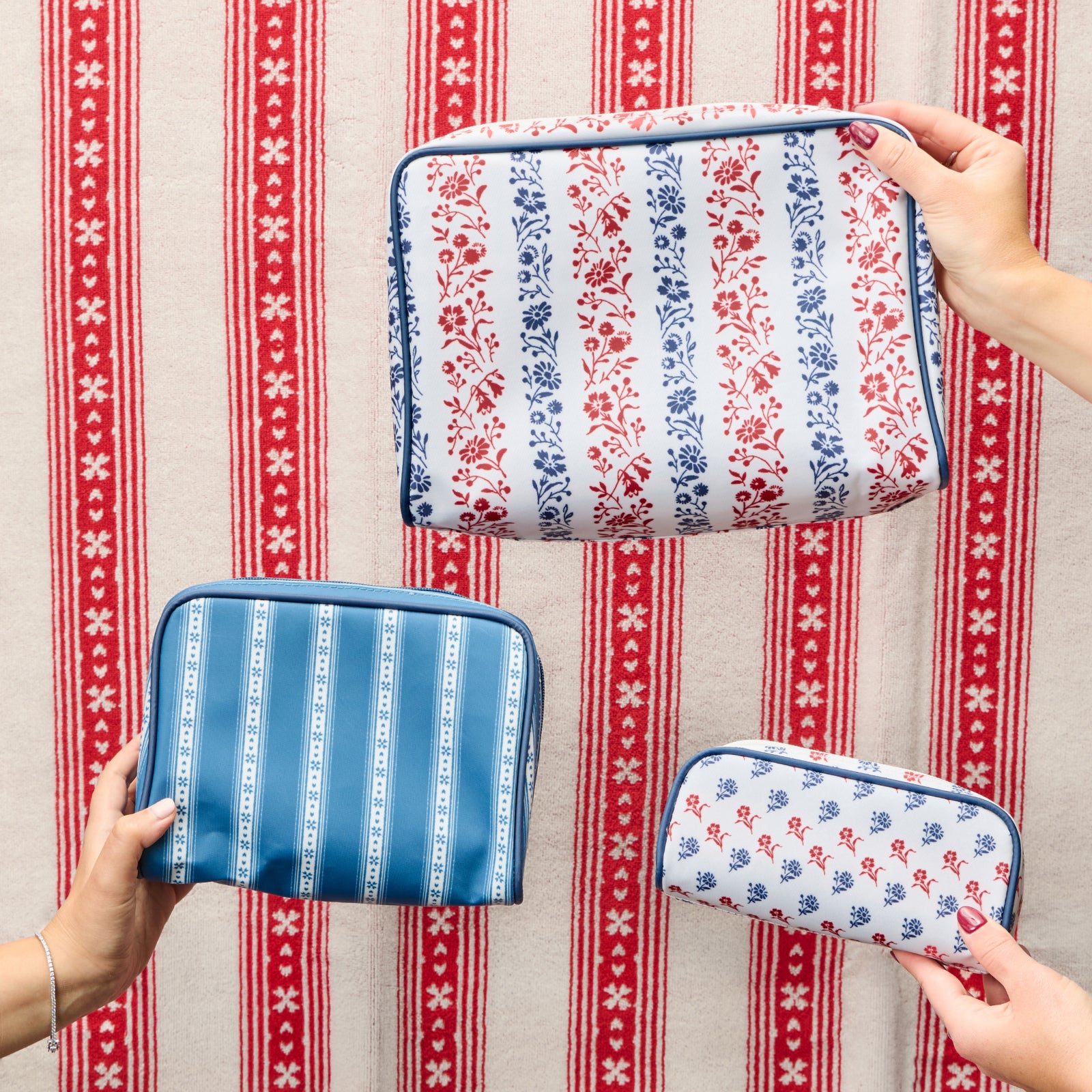 Three patterned pouches held by hands against a red and white striped background