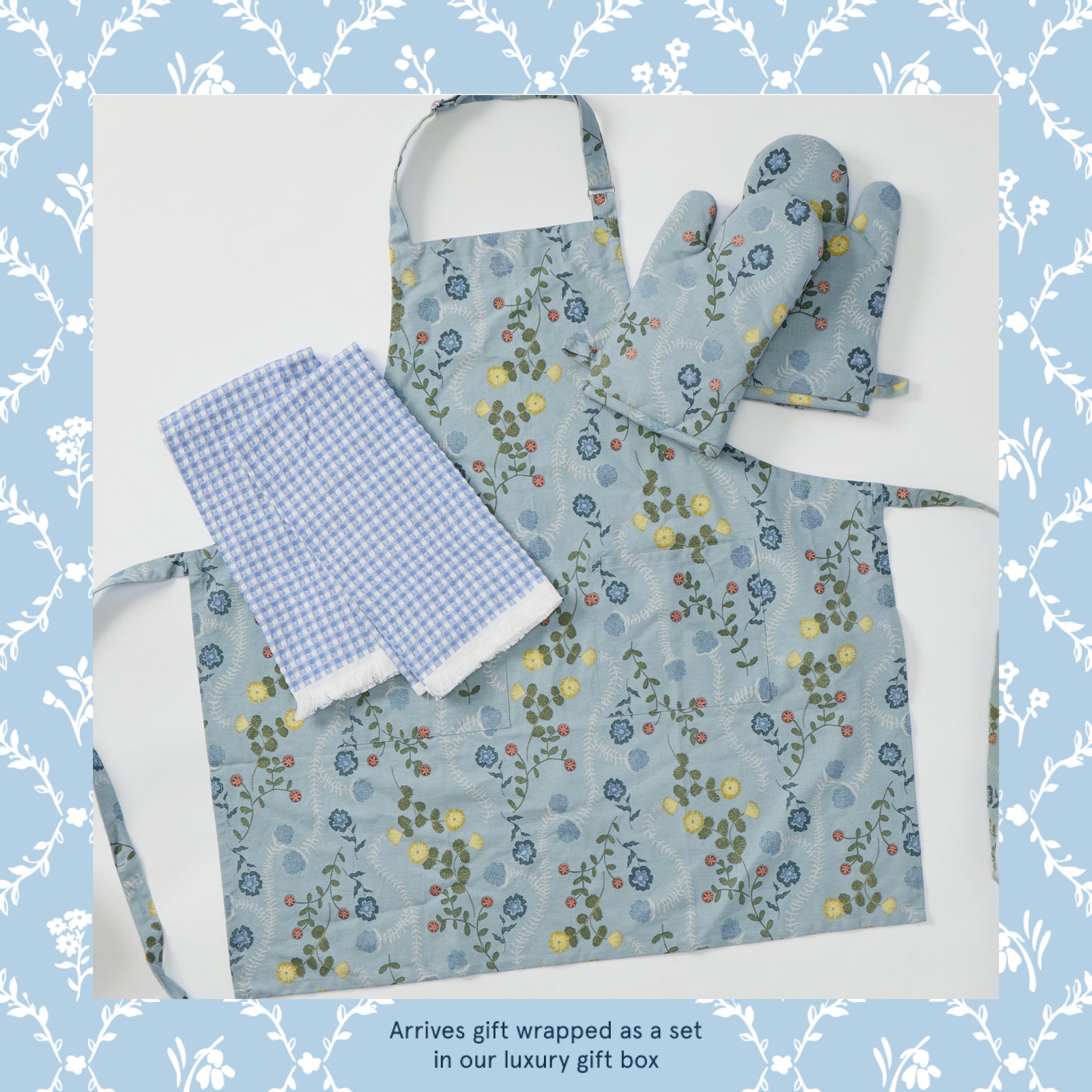 Apron, oven mitt and dish towel gift set in a blue floral vine print, laid flat
