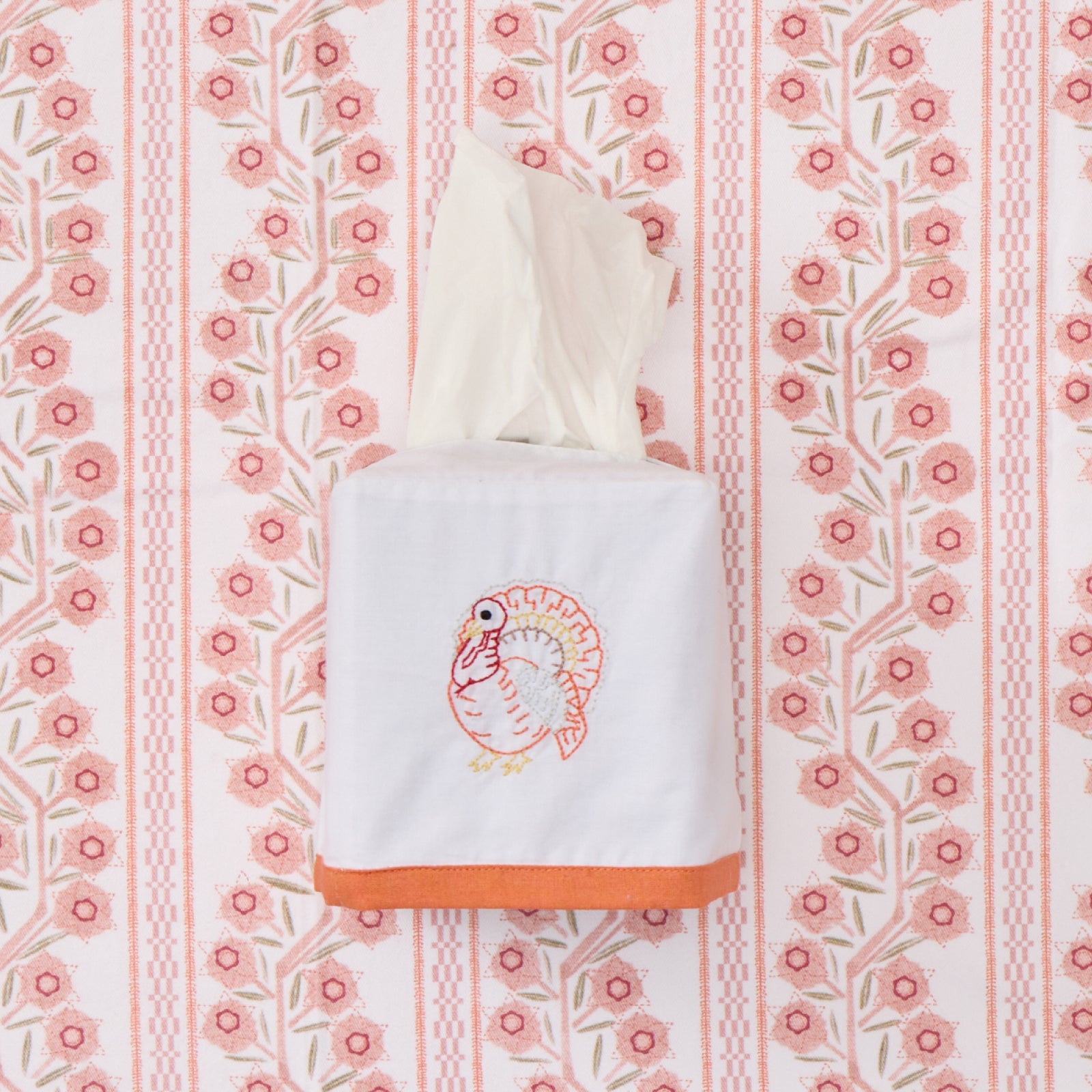 White square cotton tissue box cover with pink turkey embroidery and an orange border.