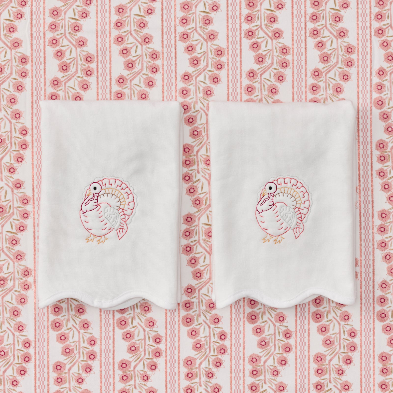 Two white powder bath towels with scalloped edges and pink embroidered turkey embroidery.