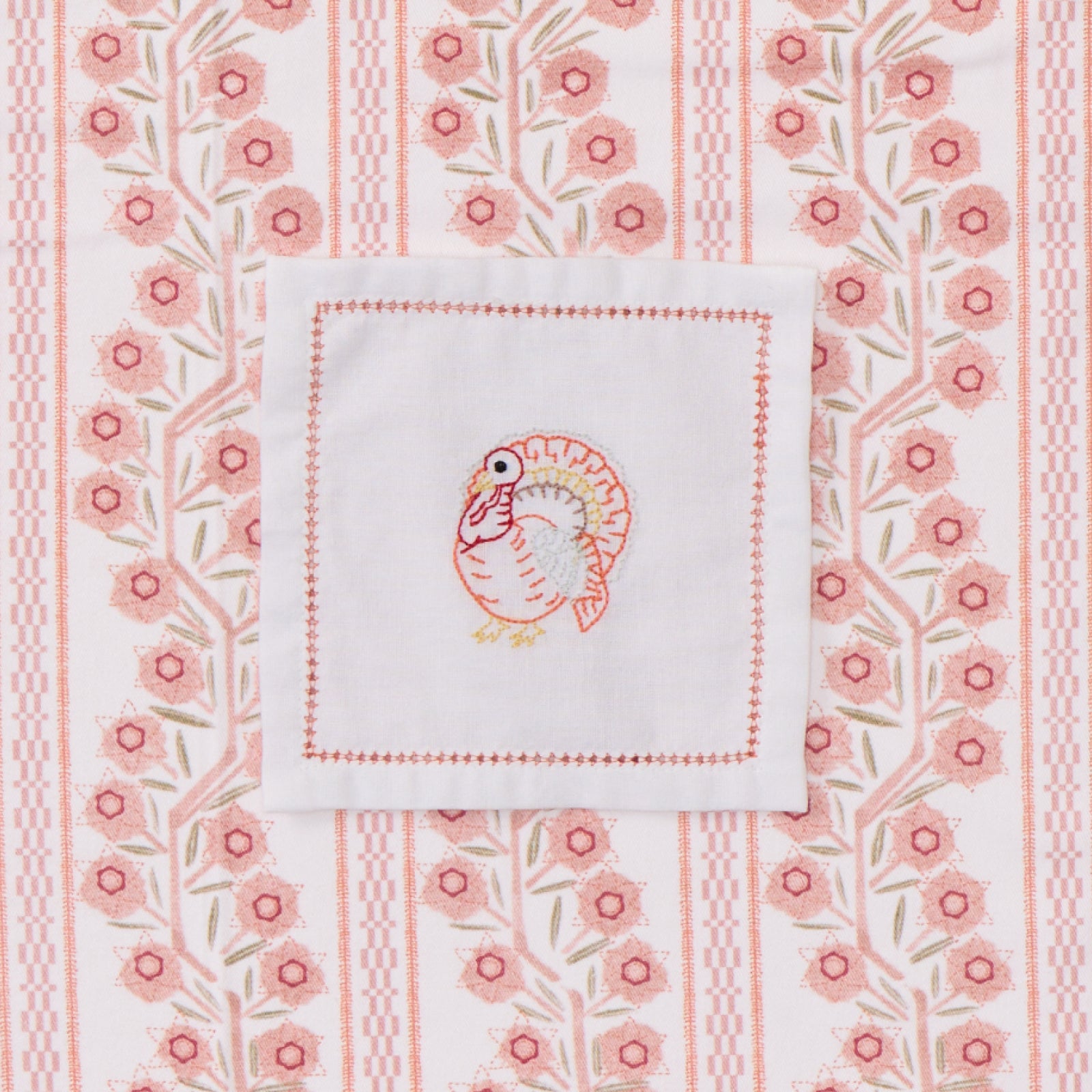 White cocktail napkin with turkey embroidery.