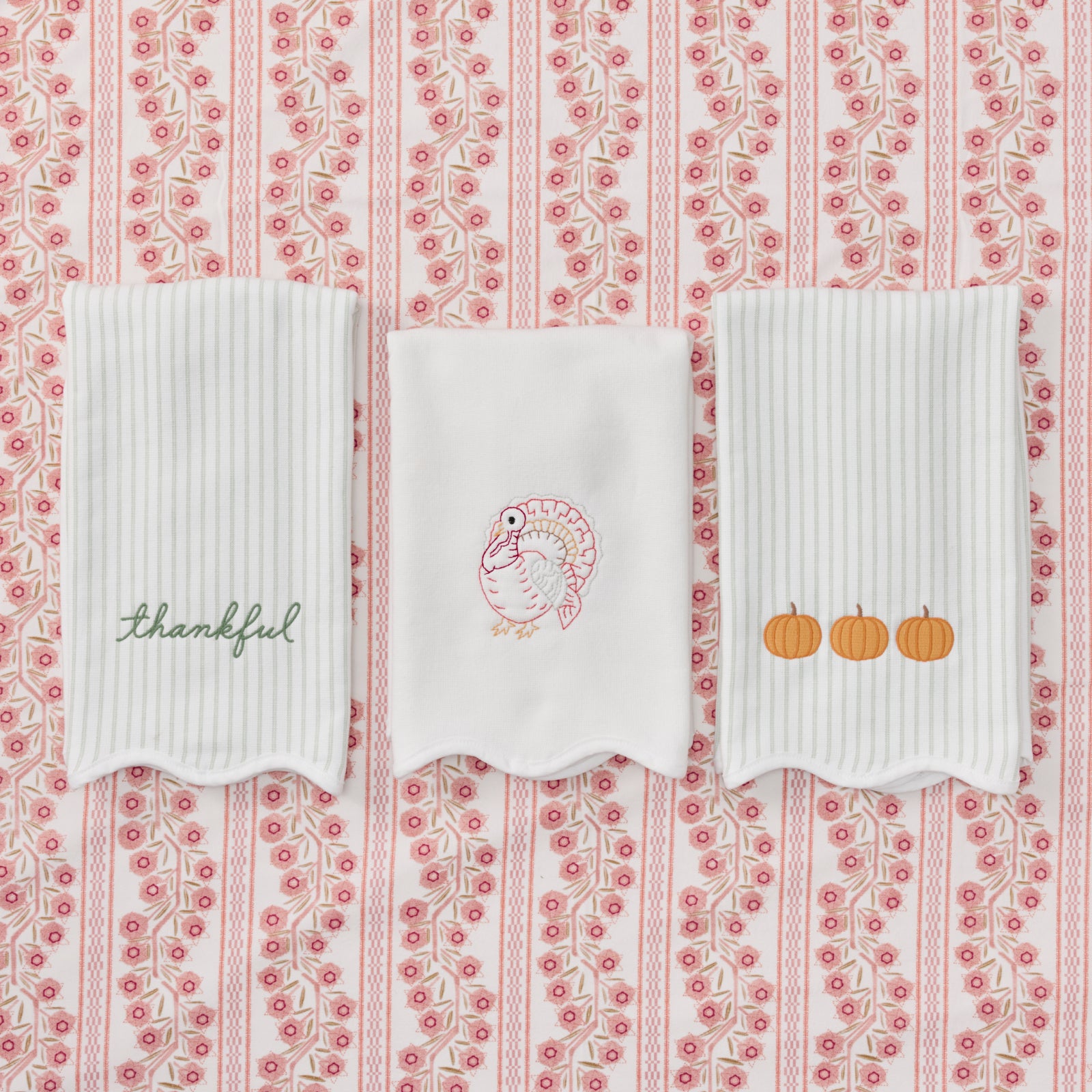 Two scalloped green striped kitchen towels featuring pumpkins and thankful embroidery with a white scalloped powder bath featuring a turkey embroidery.