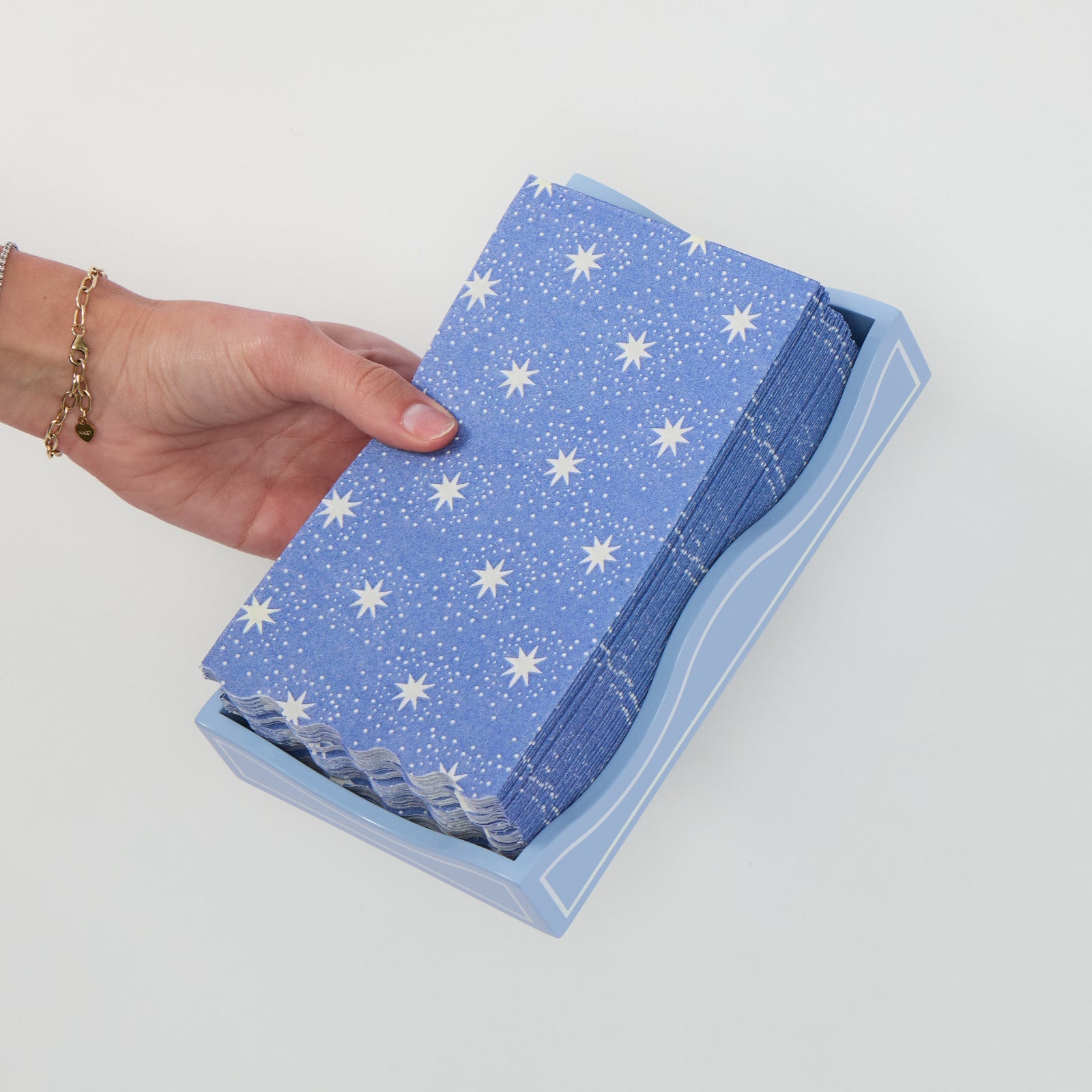 Hand placing a stack of Twilight paper guest towels into the Hydrangea lacquer tray