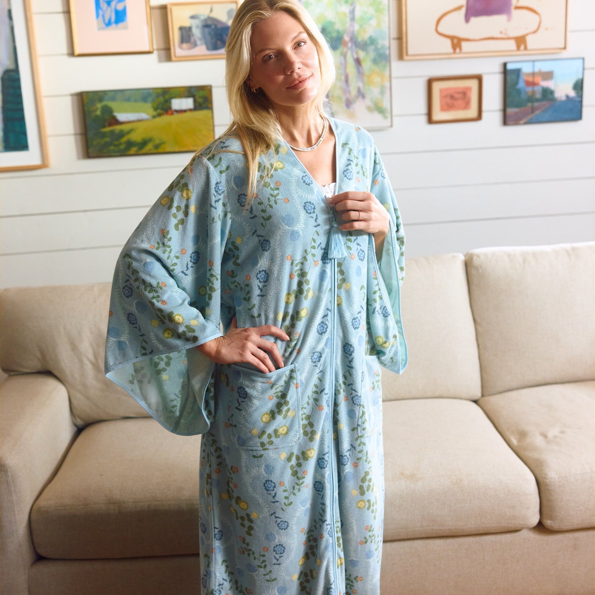 Woman wearing a long light blue floral print robe in a living room.
