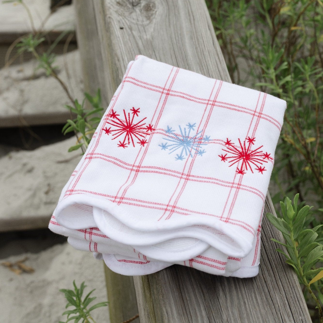 White towel with red and blue patterns on a wooden post outdoors